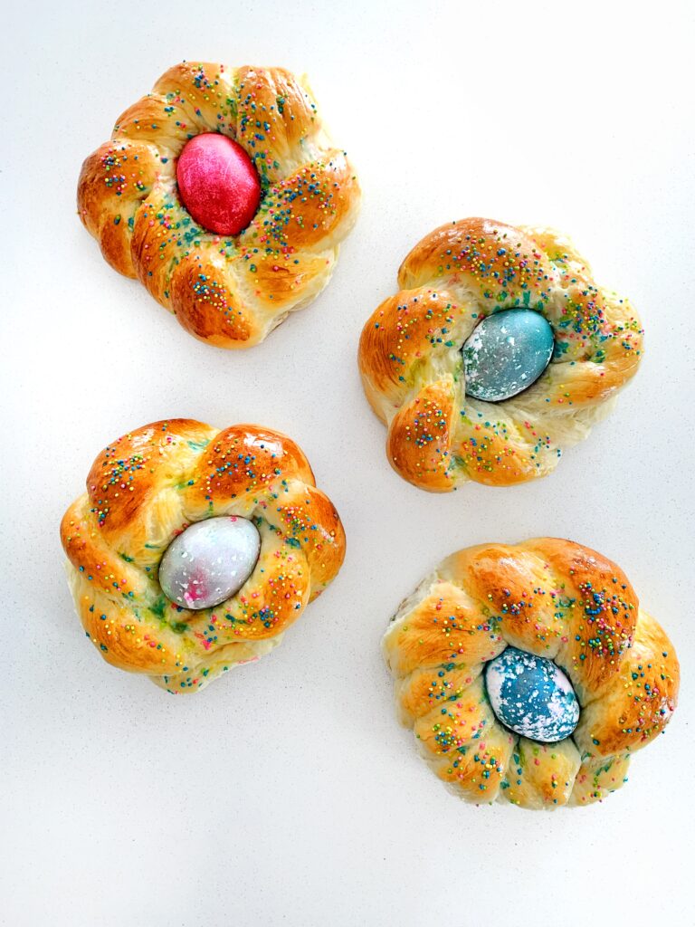 Mini pane di Pasqua breads baked until golden brown, each with a colorful Easter egg and sprinkles