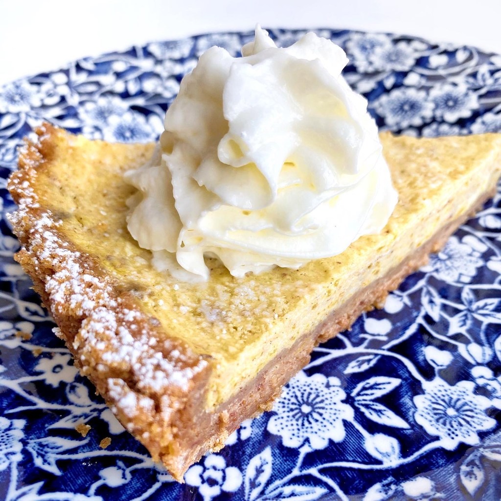 Slice of homemade pumpkin pie showing silky pumpkin filling and crisp flaky crust.