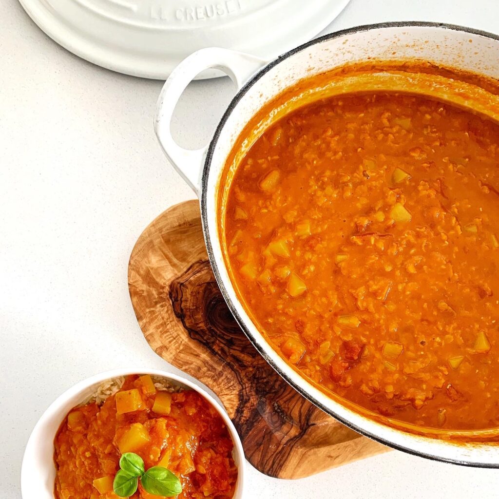 Spicy red lentil coconut curry served in a bowl with a rich tomato broth.