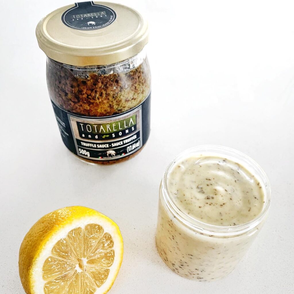 Homemade truffle aioli in a glass jar with fresh lemon and Totarella truffle sauce.
