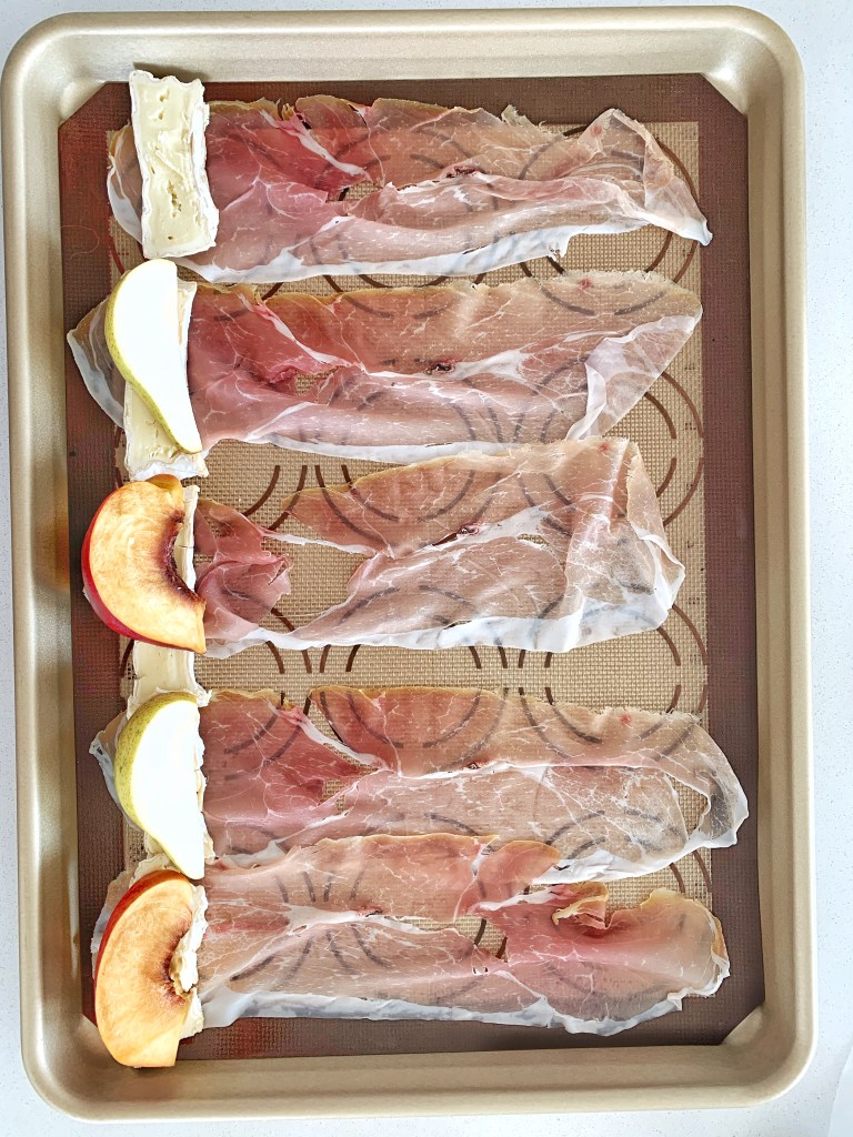 Prosciutto slices wrapped around peaches and brie before baking