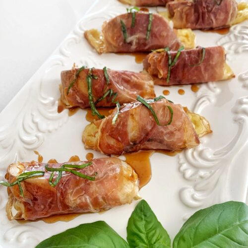 Baked prosciutto wrapped peaches with melted brie, drizzled with honey and garnished with fresh herbs
