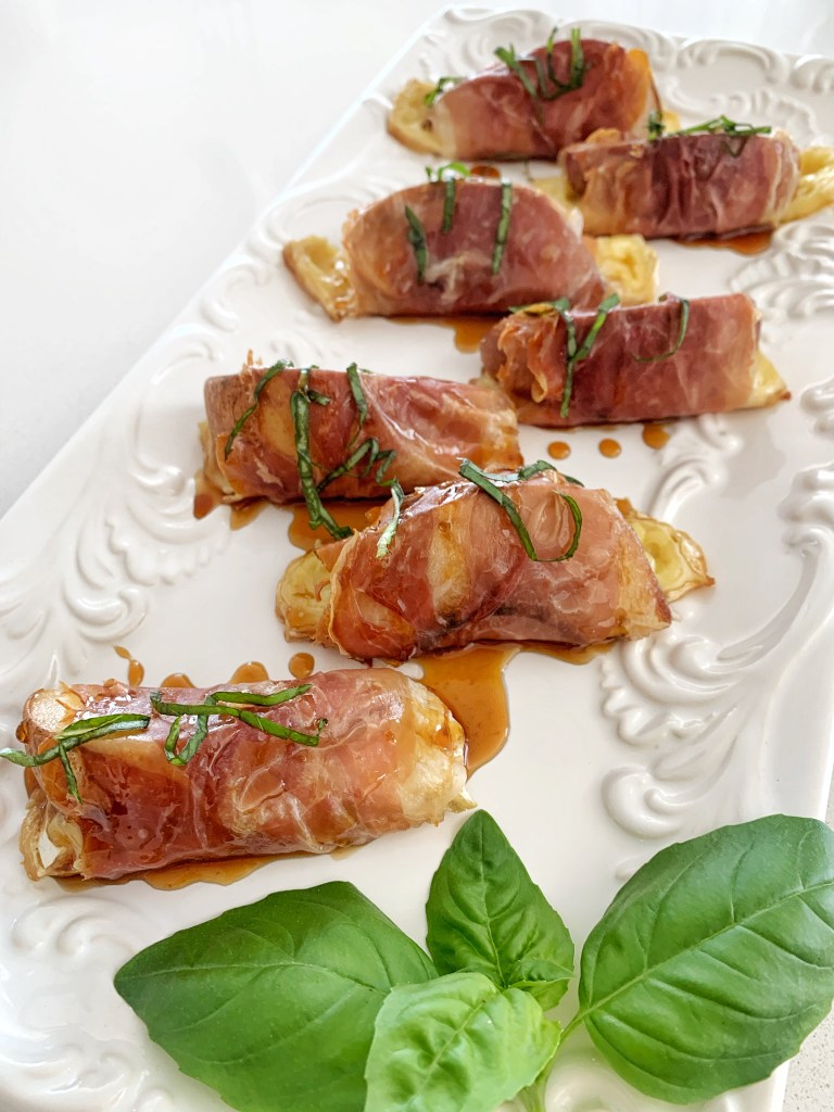 Baked prosciutto wrapped peaches with melted brie, drizzled with honey and garnished with fresh herbs
