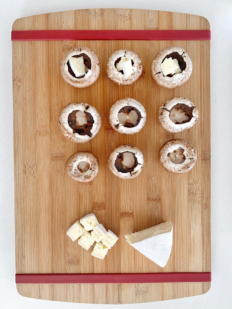 Preparing stuffed mushrooms with brie cheese for wine tasting appetizers